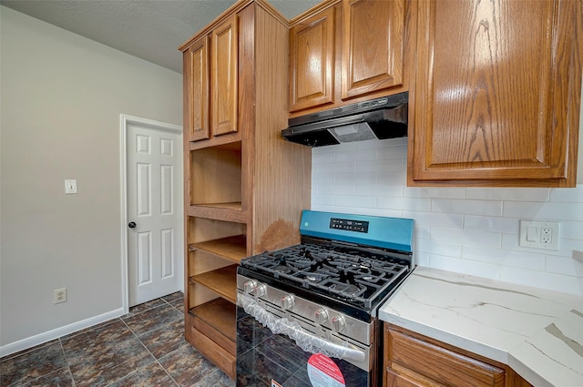 kitchen featuring decorative backsplash, light stone countertops, and stainless steel gas range