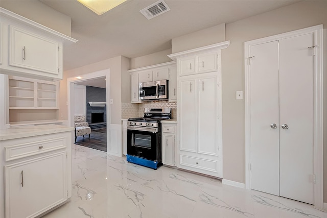 kitchen with a fireplace, decorative backsplash, white cabinetry, and black range