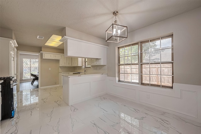 kitchen with white cabinets, stove, tasteful backsplash, and a healthy amount of sunlight