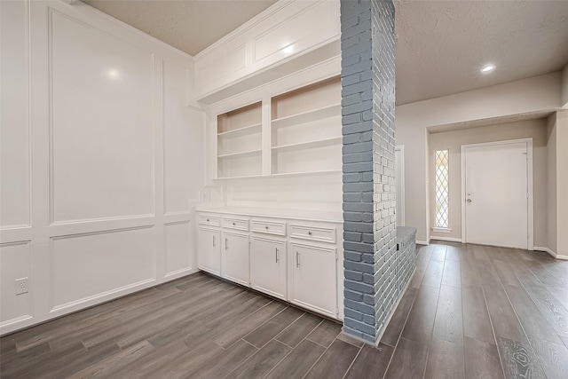 hallway featuring a textured ceiling, built in features, and dark hardwood / wood-style floors