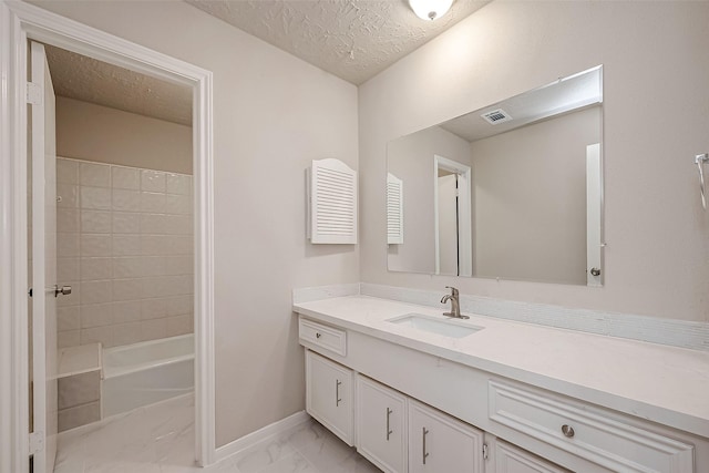 bathroom with vanity, tiled shower / bath combo, and a textured ceiling