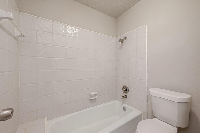 bathroom featuring a textured ceiling, toilet, and tiled shower / bath