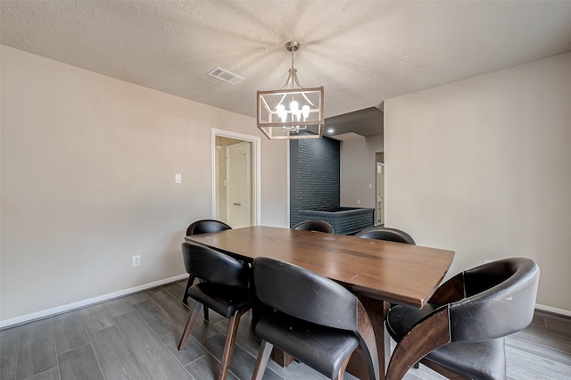 dining area with wood-type flooring, a textured ceiling, and an inviting chandelier