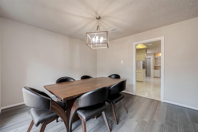 dining space with a textured ceiling, dark wood-type flooring, and a notable chandelier