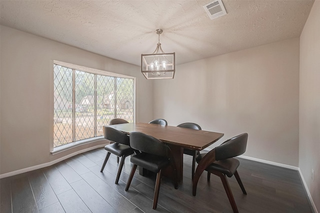 dining area with a textured ceiling, a chandelier, and dark hardwood / wood-style floors