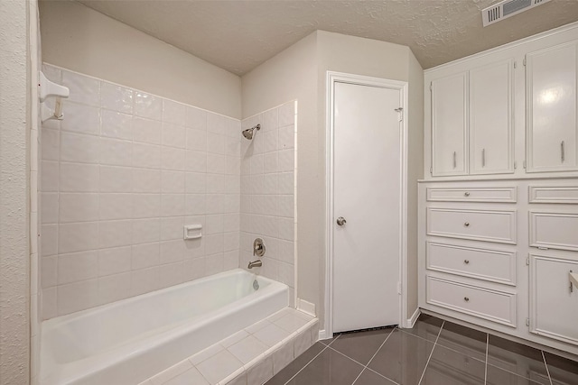 bathroom featuring a textured ceiling, tile patterned flooring, and tiled shower / bath combo