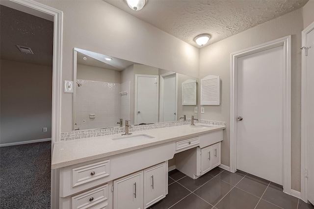 bathroom featuring a tile shower, tile patterned flooring, vanity, and a textured ceiling