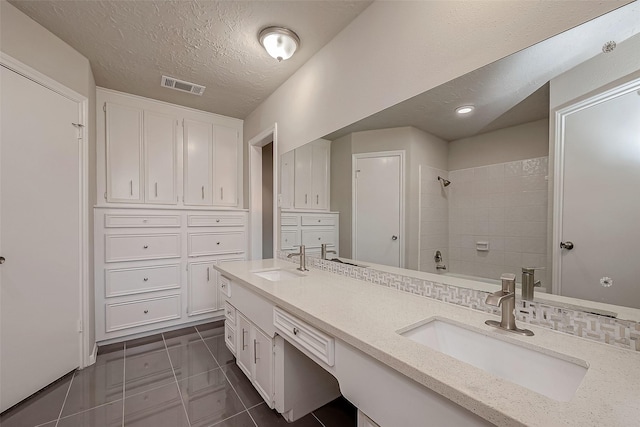 bathroom with tile patterned flooring, vanity, a textured ceiling, and tiled shower / bath combo