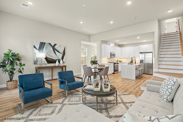 living room featuring sink and light hardwood / wood-style flooring