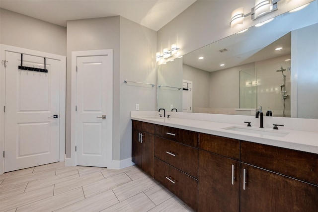 full bath with double vanity, a shower stall, baseboards, and a sink