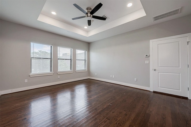 unfurnished room featuring dark wood-type flooring, a raised ceiling, visible vents, and baseboards