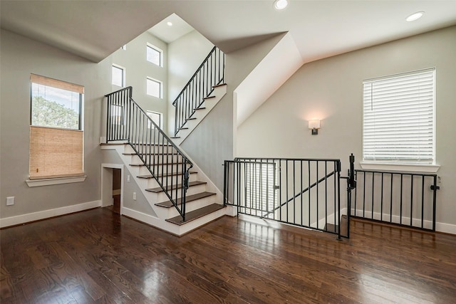 stairway with recessed lighting, a high ceiling, baseboards, and wood finished floors