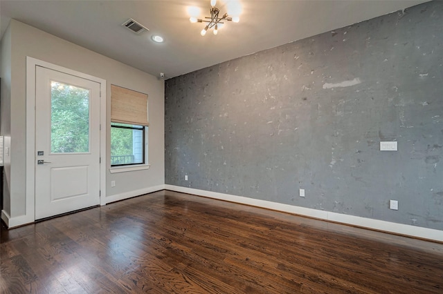 unfurnished room featuring baseboards, visible vents, a chandelier, and wood finished floors