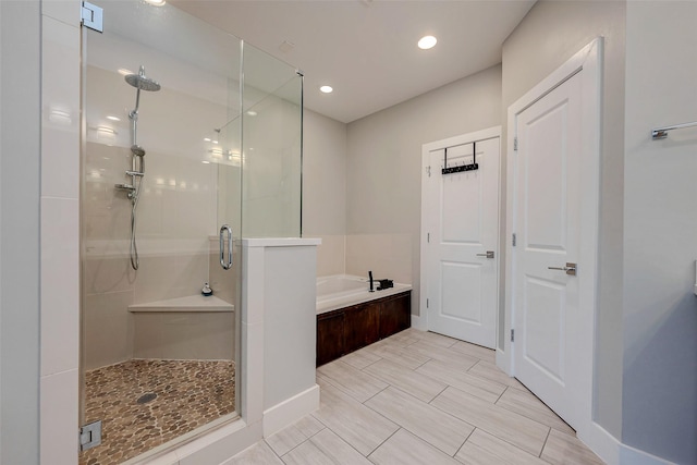 bathroom with a stall shower, a garden tub, and recessed lighting