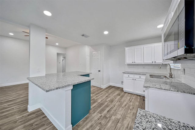 kitchen with backsplash, light hardwood / wood-style floors, white cabinetry, and sink