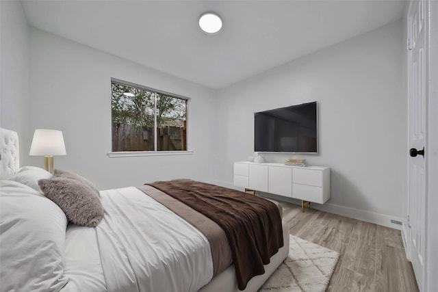 bedroom with light wood-type flooring and lofted ceiling