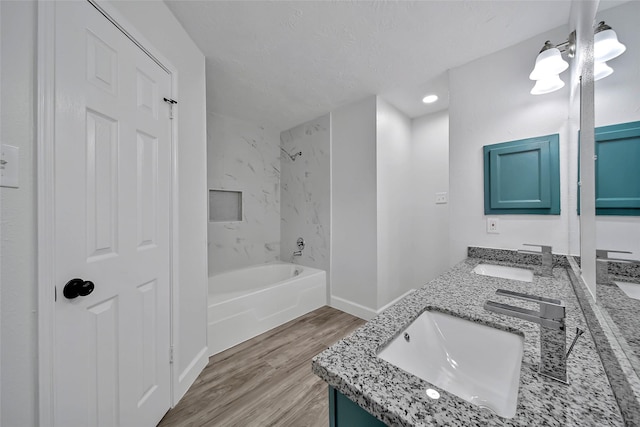 bathroom with vanity, a textured ceiling, wood-type flooring, an inviting chandelier, and tiled shower / bath