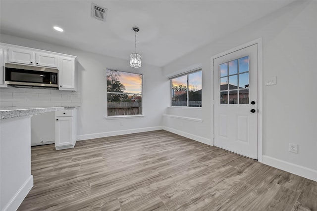 unfurnished dining area with light hardwood / wood-style floors and an inviting chandelier