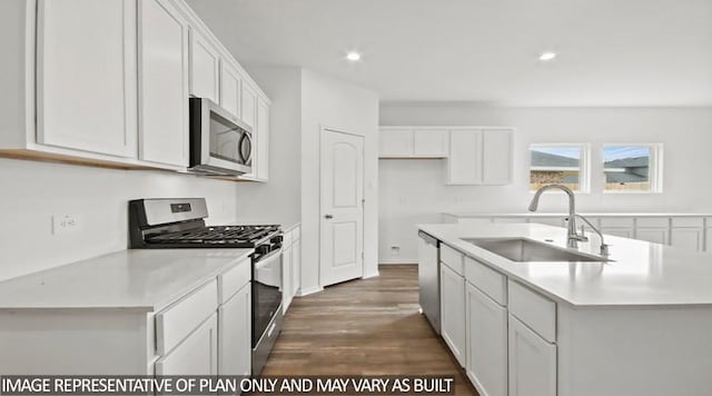 kitchen with appliances with stainless steel finishes, an island with sink, white cabinetry, and sink