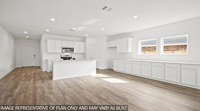 kitchen with white cabinetry, an island with sink, appliances with stainless steel finishes, and light hardwood / wood-style flooring