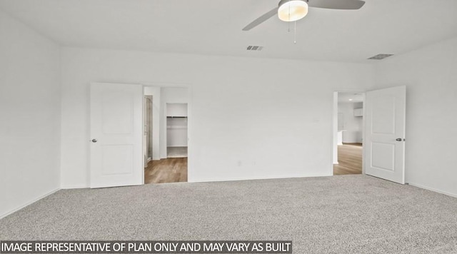 unfurnished bedroom featuring ceiling fan, a spacious closet, carpet floors, and a closet