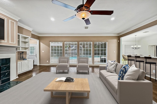 living room with a fireplace, dark hardwood / wood-style flooring, ceiling fan with notable chandelier, and ornamental molding