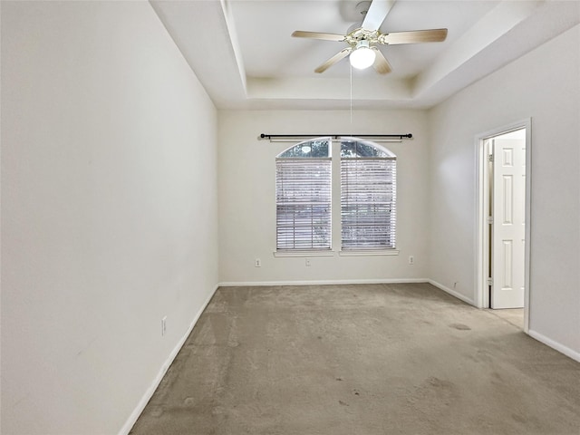 carpeted empty room featuring ceiling fan and a tray ceiling