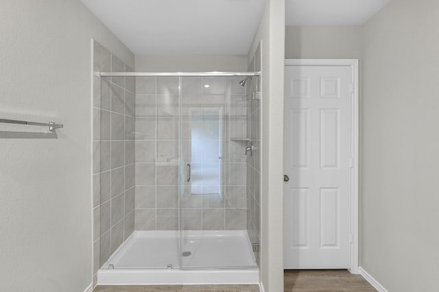 bathroom with hardwood / wood-style flooring and a shower with door