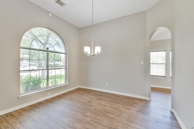 unfurnished room featuring vaulted ceiling, hardwood / wood-style flooring, and a notable chandelier