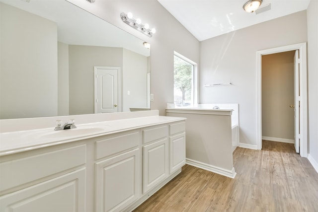 bathroom with a washtub, vanity, and hardwood / wood-style flooring