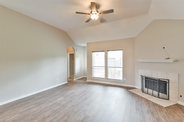 unfurnished living room featuring lofted ceiling, a tiled fireplace, light wood-type flooring, and ceiling fan