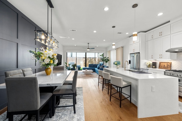 dining space with ceiling fan, sink, and light hardwood / wood-style floors