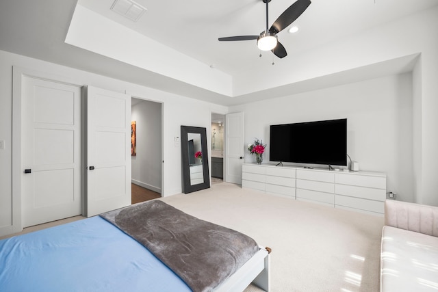 carpeted bedroom featuring a tray ceiling and ceiling fan