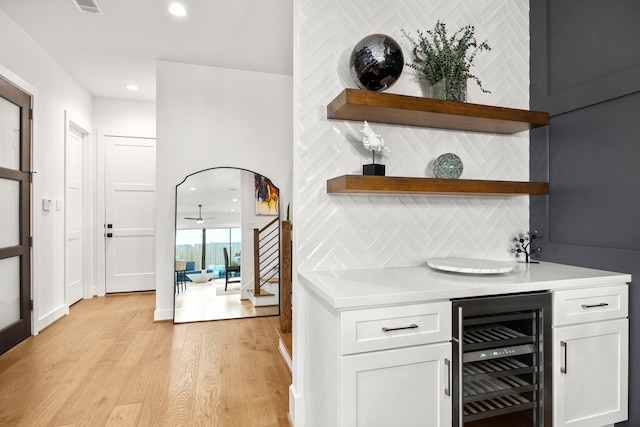 bar featuring white cabinetry, wine cooler, tasteful backsplash, and light hardwood / wood-style floors