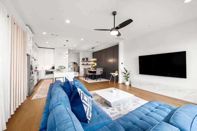 living room with light hardwood / wood-style floors and ceiling fan