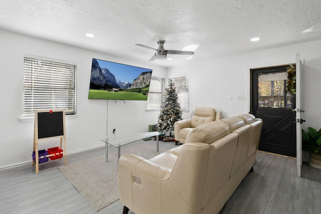 living room featuring a textured ceiling, hardwood / wood-style floors, and ceiling fan