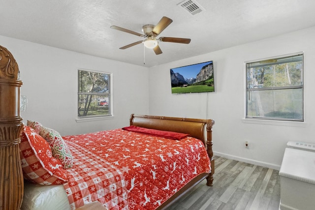 bedroom with ceiling fan, a textured ceiling, and hardwood / wood-style flooring