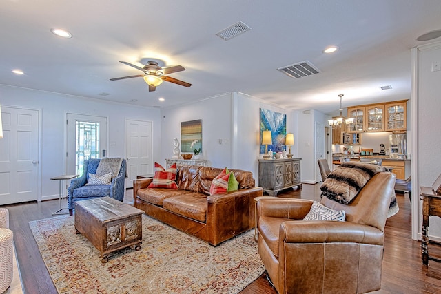 living room featuring hardwood / wood-style floors, ceiling fan with notable chandelier, and ornamental molding