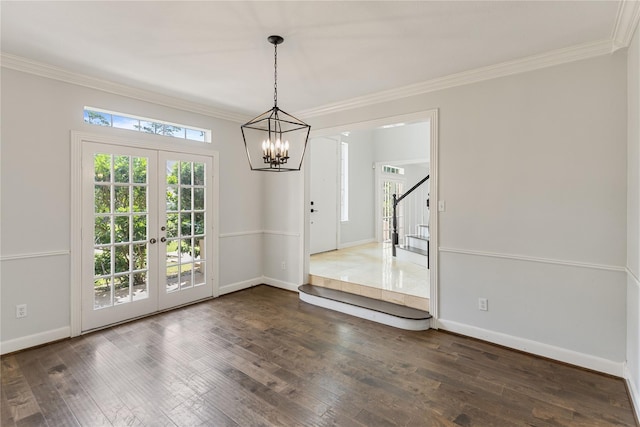 empty room with an inviting chandelier, dark hardwood / wood-style flooring, ornamental molding, and french doors