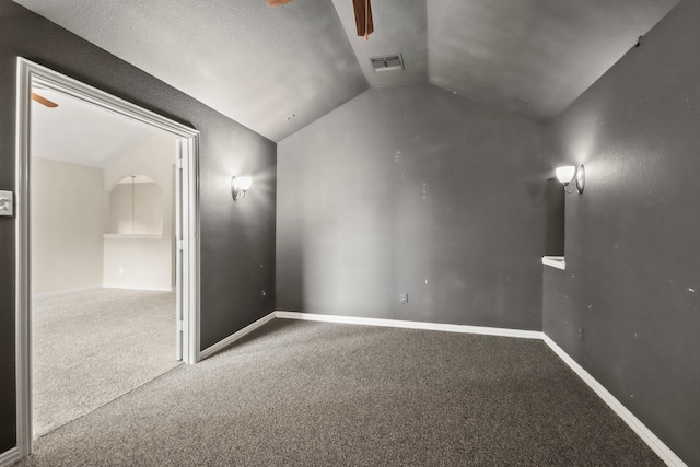 empty room with ceiling fan, carpet floors, a textured ceiling, and vaulted ceiling