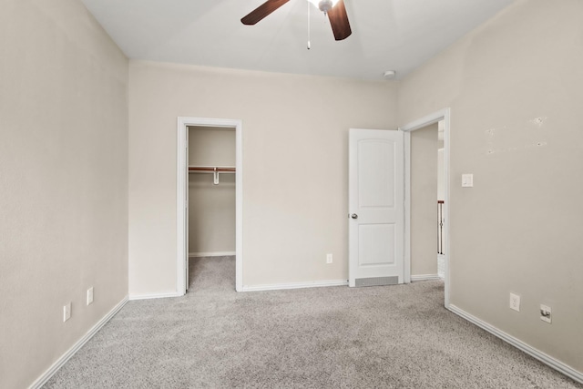 unfurnished bedroom featuring ceiling fan, a closet, a spacious closet, and light carpet