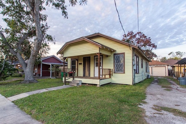 bungalow with an outbuilding, a garage, a front lawn, and covered porch