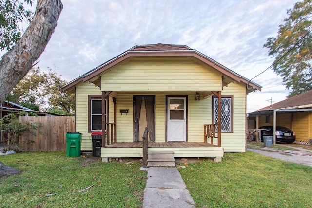 bungalow with a front yard, a porch, and a carport