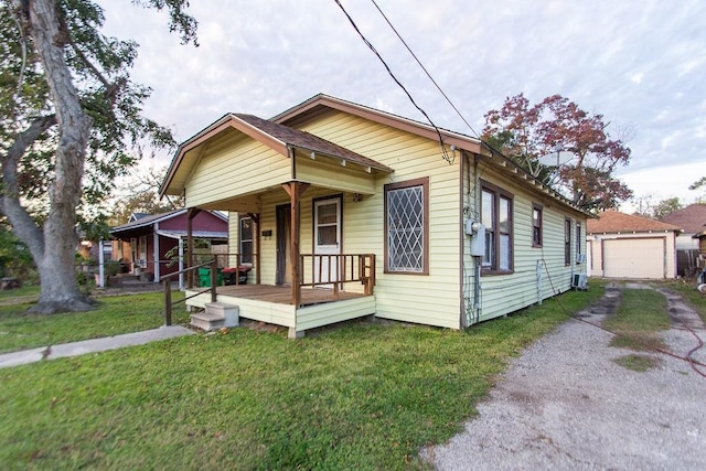 bungalow-style house featuring a front lawn, covered porch, an outdoor structure, and a garage