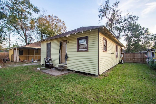 back of house featuring a lawn and central air condition unit