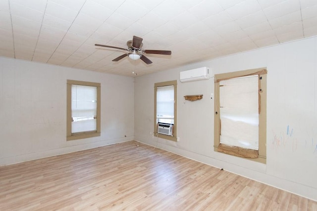 empty room with a wall unit AC, ceiling fan, cooling unit, and light hardwood / wood-style floors