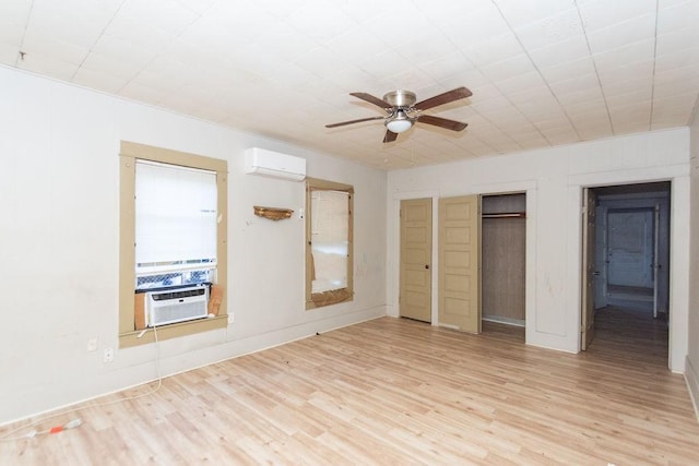 unfurnished bedroom featuring a wall mounted AC, cooling unit, ceiling fan, light hardwood / wood-style flooring, and multiple closets