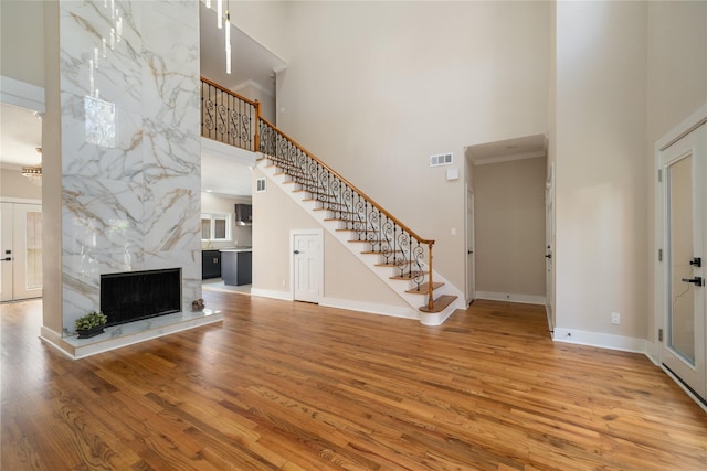 unfurnished living room featuring a premium fireplace, wood-type flooring, and a high ceiling