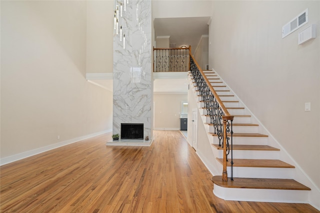 staircase featuring hardwood / wood-style floors, a premium fireplace, and a towering ceiling