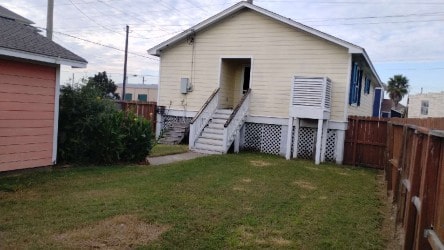 back of house featuring a fenced backyard and a lawn